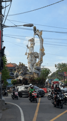 Ornate deity statue documented in sunny Ubud street scene