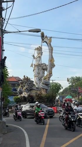 Ornate deity statue documented in sunny Ubud street scene