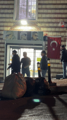 Evening gathering outside Istanbul storefront with Turkish flag