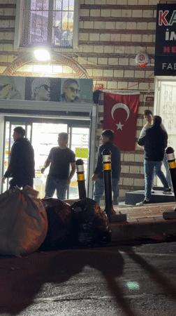 Evening gathering outside Istanbul storefront with Turkish flag