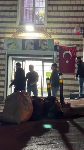Evening gathering outside Istanbul storefront with Turkish flag