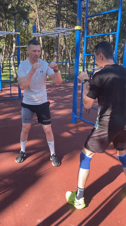 Outdoor boxing drills on a rubberized park court, plus one sleepy cat