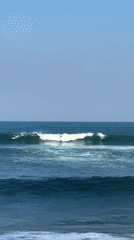 Casual surf session, clear skies, waves breaking steady.