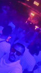 Nightclub crowd under purple and blue lights, red sunglasses in frame