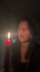 Woman extinguishes red candle in darkened Montenegro room