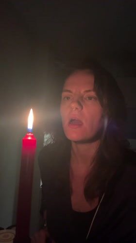 Woman extinguishes red candle in darkened Montenegro room
