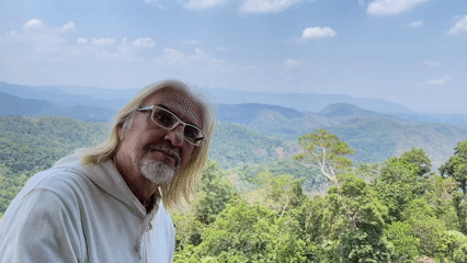 Man in white hoodie observed against green hills in Vietnam