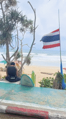 Motorcyclist rides past busy Karon Beach in Thailand
