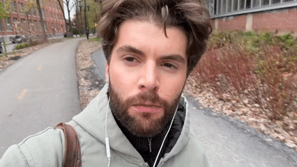 Man walks Montreal campus taking selfies on overcast evening