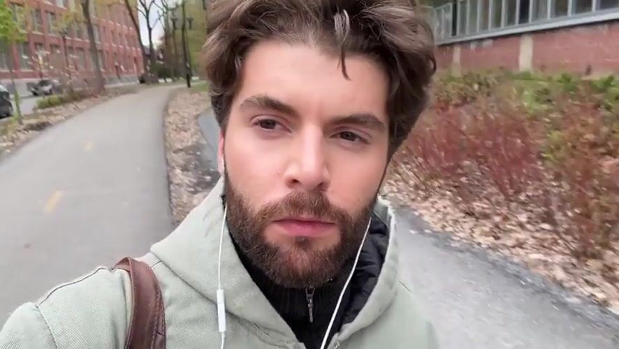 Man walks Montreal campus taking selfies on overcast evening