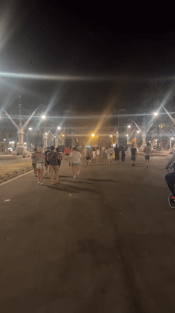 Late-night crowd gathers at lit Barcelona archway, jerseys and all