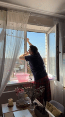 Man cleans window at home wearing pajamas