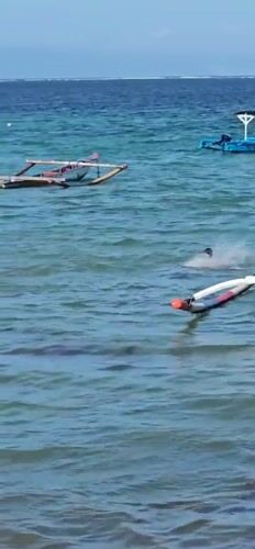 Morning beach activity observed in Denpasar with swimmers and boats