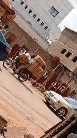 Motorcyclist carries cardboard boxes through Maiburiji street