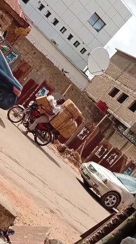 Motorcyclist carries cardboard boxes through Maiburiji street