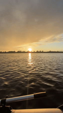 Inflatable boat on a Russian river, sunset into rainbow