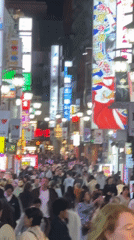 Busy nighttime crowds fill neon-lit Shinjuku streets