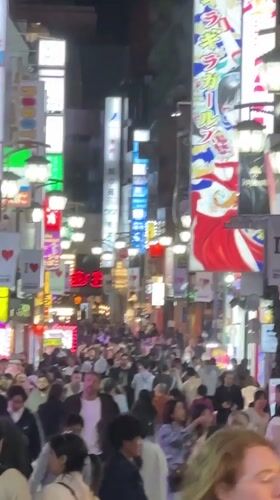 Busy nighttime crowds fill neon-lit Shinjuku streets