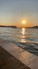 Golden sunset reflects off rippling water near a city skyline