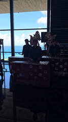Three musicians play wooden percussion by ocean in Kuta Selatan