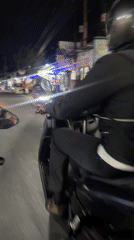 Nighttime motorcycle traffic filmed on vendor-lined Kuta Selatan road