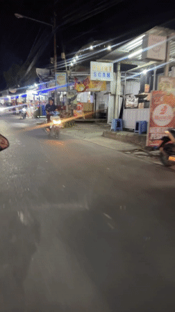 Nighttime motorcycle traffic filmed on vendor-lined Kuta Selatan road