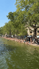 Parisians cool off along a city canal on a summer day