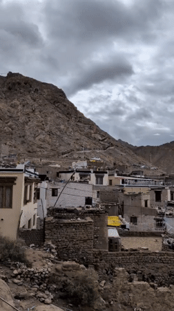 Dense village in a rocky valley under stormy skies