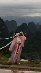 Woman poses in traditional Hanfu with ribbons on Guilin hilltop