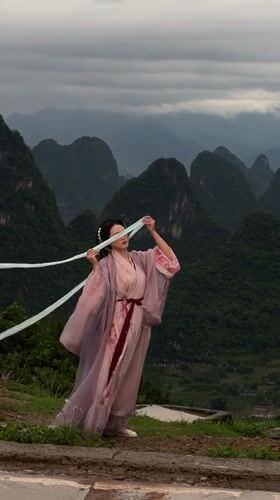 Woman poses in traditional Hanfu with ribbons on Guilin hilltop