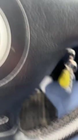 The video shows a first-person perspective from inside a Volkswagen car driving on a rural road. The dashboard and steering wheel are in focus, with the Volkswagen logo visible on the steering wheel. A set of keys hangs from the ignition. The car is driving on a paved road through a landscape of green fields and distant mountains under a cloudy sky. As the car moves forward, a sign in Cyrillic reading "Чернозем Ch. nozer" comes into view.