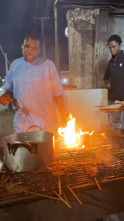 Street vendors cook meat skewers at night stalls in Ado