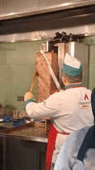 Chef slices meat from rotisserie grill in Vienna