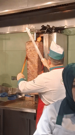 Chef slices meat from rotisserie grill in Vienna