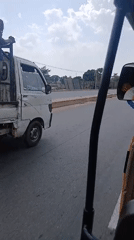 Three people ride in back of moving white mini-truck