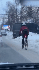 Cyclist rides snow-covered Kazan street during winter morning
