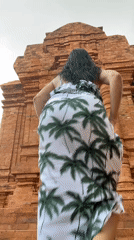Woman in tropical print dress observed at Vietnam brick structure