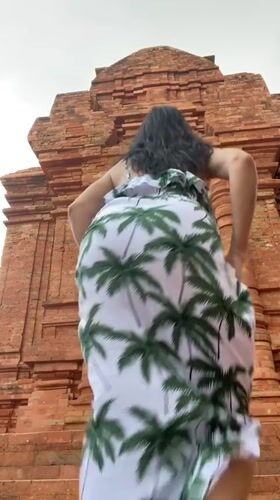 Woman in tropical print dress observed at Vietnam brick structure