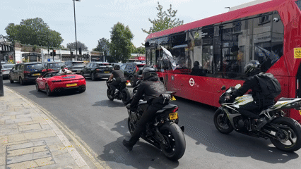 Motorcyclists rev engines amid heavy traffic on sunny London street