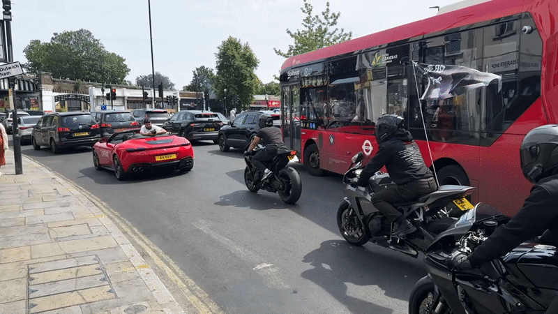 Motorcyclists rev engines amid heavy traffic on sunny London street