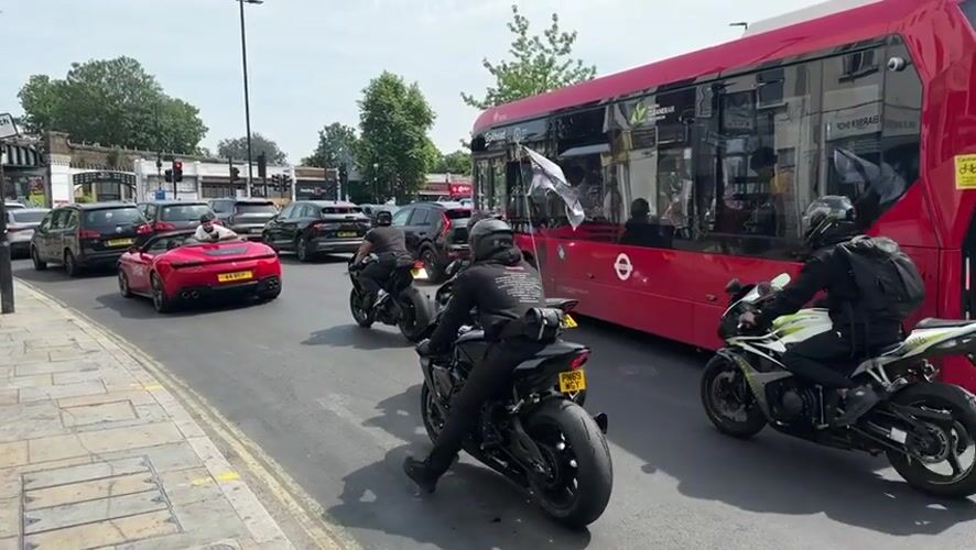 Motorcyclists rev engines amid heavy traffic on sunny London street