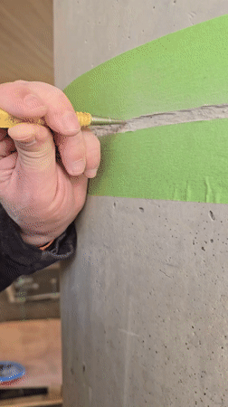 Worker chips concrete from marked column in Herzliya