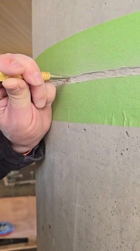 Worker chips concrete from marked column in Herzliya