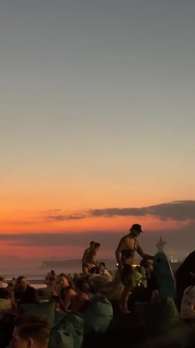 Kuta Beach at golden hour — crowds, dogs, and sunset light