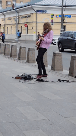 Electric guitar played on a city sidewalk, balloons drifting nearby