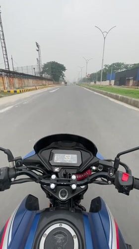 Motorcyclist rides blue Honda on empty Panchkhola road