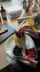 Person creates pineapple cake with berries, gold candles in London