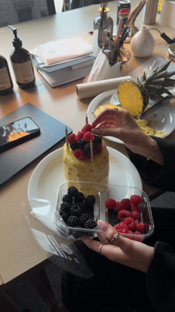 Person creates pineapple cake with berries, gold candles in London