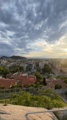 City sunset captured from elevated viewpoint shows red-roofed buildings