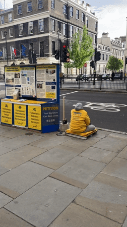 Person in Falun Dafa sweatshirt sits on London sidewalk